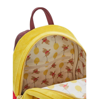 The inside view of a yellow mini backpack featuring a pattern of Winnie the Pooh floating with yellow balloons. There is a small zippered pocket inside.