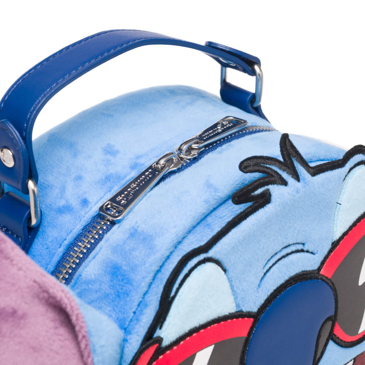 Close-up of the blue zipper and handle on the top of the mini backpack.